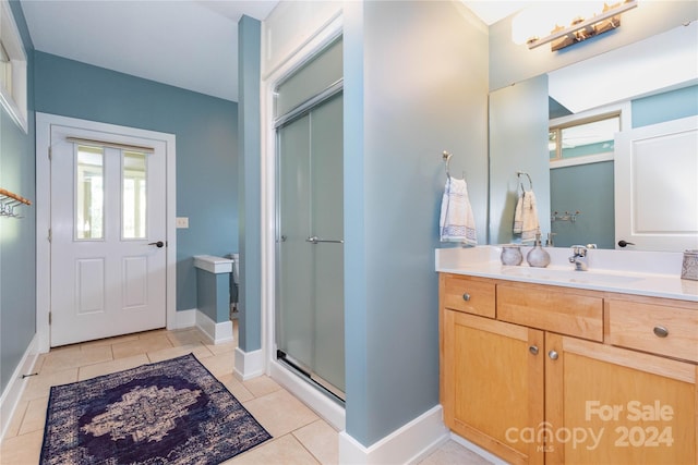 bathroom featuring tile patterned floors, a shower with door, and vanity