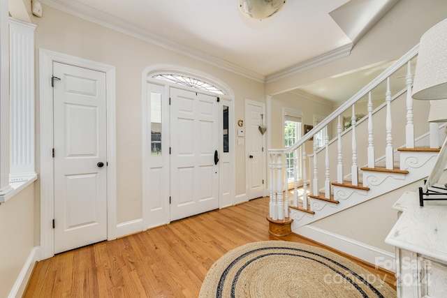 entrance foyer with stairway, baseboards, light wood-style floors, and ornamental molding