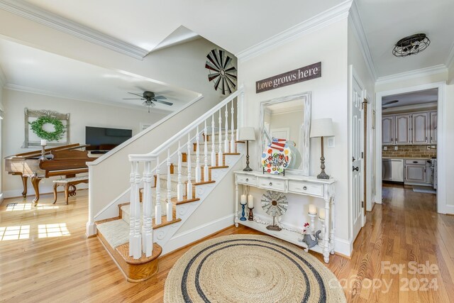 stairs featuring crown molding, hardwood / wood-style floors, and ceiling fan