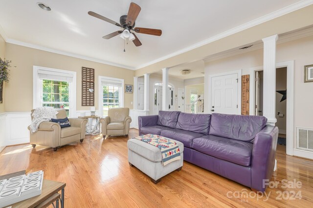 living room featuring ornamental molding, light hardwood / wood-style flooring, ornate columns, and ceiling fan