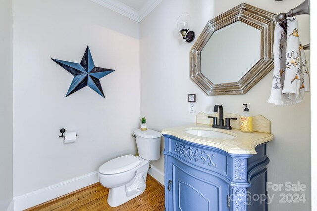 bathroom featuring vanity, toilet, ornamental molding, and hardwood / wood-style flooring