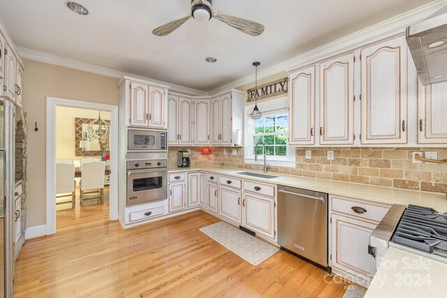 kitchen with light wood-type flooring, appliances with stainless steel finishes, sink, ceiling fan, and pendant lighting