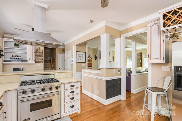 kitchen with light wood-type flooring, crown molding, island exhaust hood, ornate columns, and luxury stove