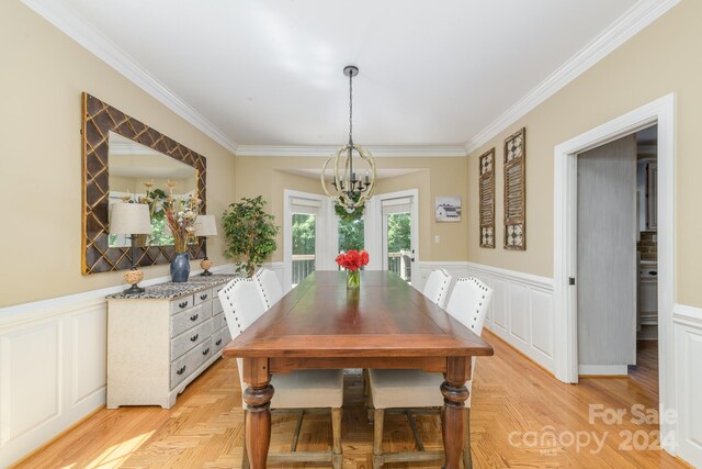 dining area featuring ornamental molding, light parquet flooring, and an inviting chandelier