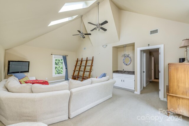 living room featuring carpet, ceiling fan, high vaulted ceiling, and a skylight