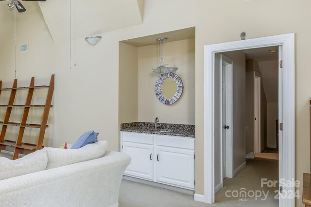 interior space with white cabinets, light carpet, sink, and ceiling fan