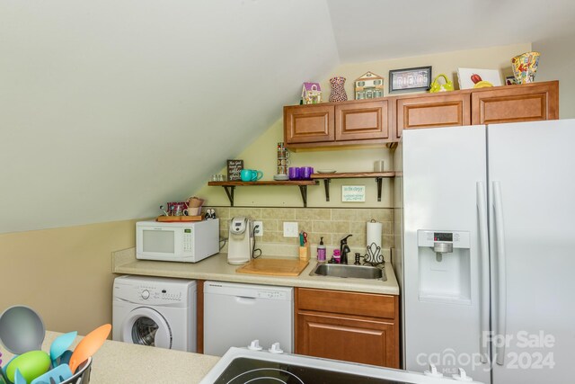 kitchen featuring white appliances, tasteful backsplash, sink, washer / dryer, and lofted ceiling