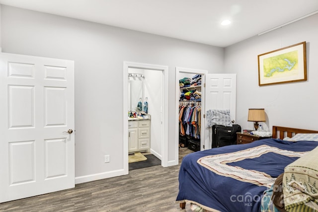 bedroom with connected bathroom, hardwood / wood-style flooring, a walk in closet, and a closet