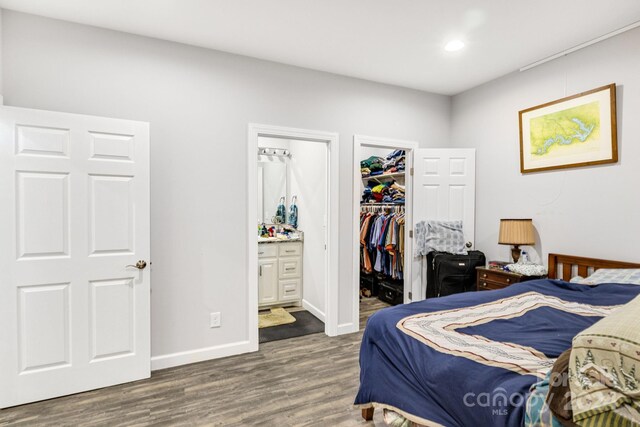 202 Ivy Ct, Morganton, NC 28655 - bedroom featuring a walk in closet, wood finished floors, connected bathroom, a closet, and baseboards
