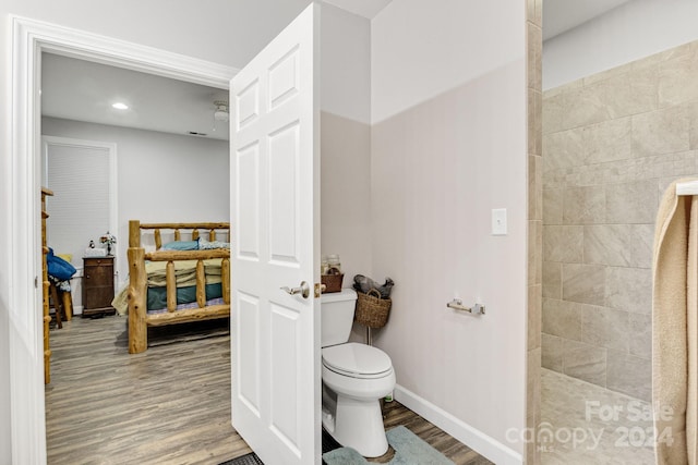 bathroom featuring toilet, hardwood / wood-style flooring, and a tile shower