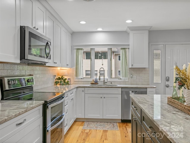 kitchen featuring stainless steel appliances, sink, light wood-type flooring, and white cabinetry