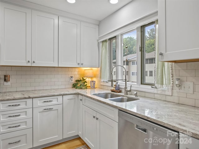 kitchen featuring white cabinetry, dishwasher, light stone counters, sink, and decorative backsplash