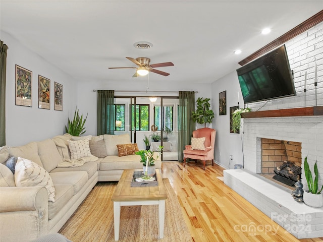 living room featuring ceiling fan, a fireplace, and light hardwood / wood-style floors