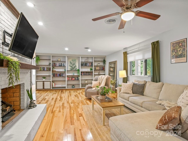 living room with a fireplace, light wood-type flooring, and ceiling fan