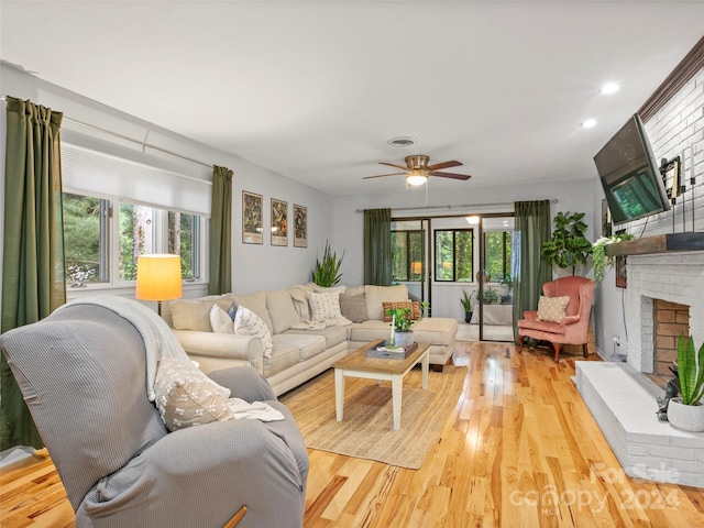 living room featuring a brick fireplace, ceiling fan, and light hardwood / wood-style floors