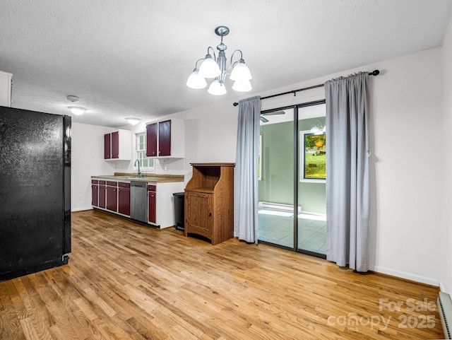 kitchen featuring black refrigerator, stainless steel dishwasher, light wood-type flooring, a textured ceiling, and a chandelier