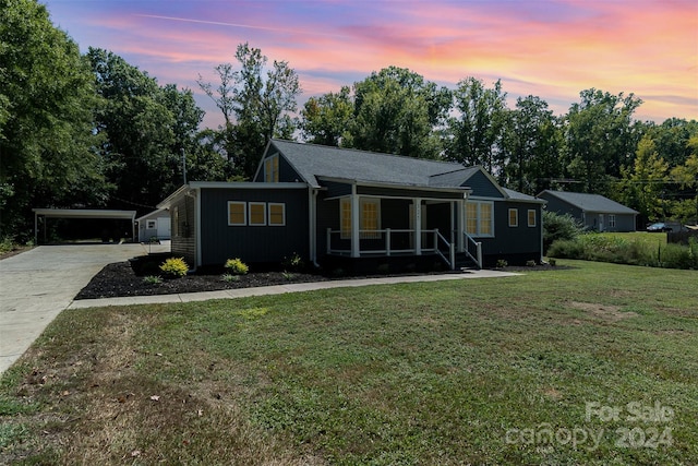 ranch-style house featuring a lawn, a carport, and a porch