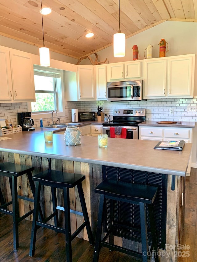 kitchen featuring white cabinetry, wood ceiling, stainless steel appliances, and a breakfast bar