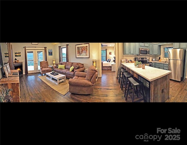 living room featuring sink, dark hardwood / wood-style floors, french doors, and a towering ceiling