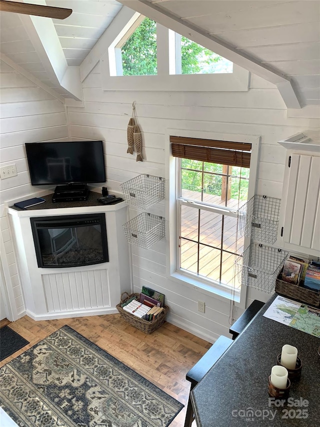 living room with lofted ceiling, plenty of natural light, hardwood / wood-style floors, and wood walls