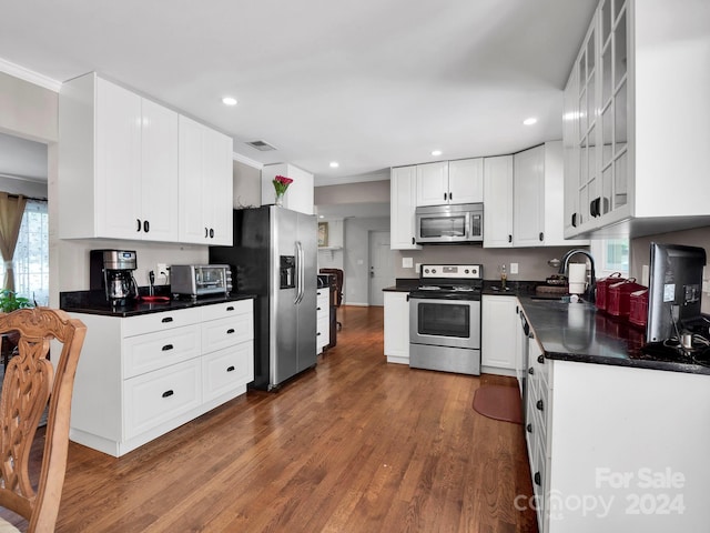 kitchen featuring dark wood-type flooring, stainless steel appliances, ornamental molding, sink, and white cabinetry