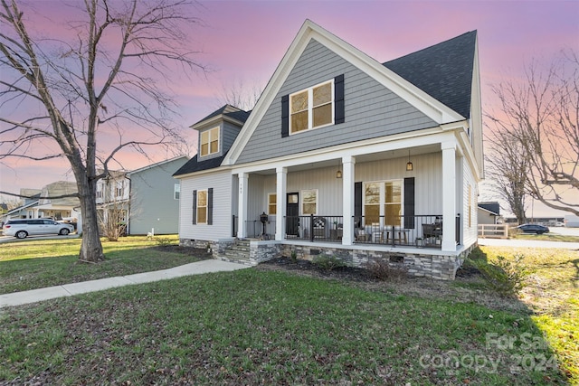 view of front of property with a porch and a yard