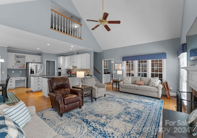 living room featuring high vaulted ceiling, light hardwood / wood-style floors, ceiling fan, and a fireplace