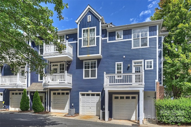 view of property featuring a garage, a balcony, and central AC unit