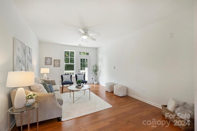 living room featuring dark wood-type flooring and ceiling fan