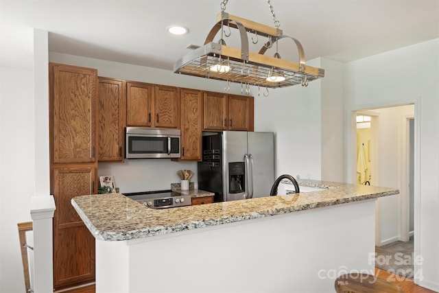 kitchen featuring light stone counters, stainless steel appliances, and kitchen peninsula