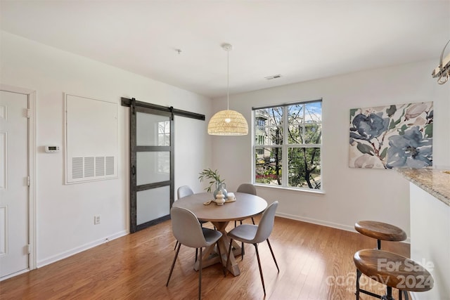 dining space with hardwood / wood-style floors and a barn door