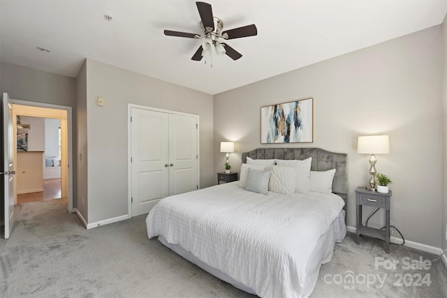 bedroom featuring light colored carpet, ceiling fan, and a closet