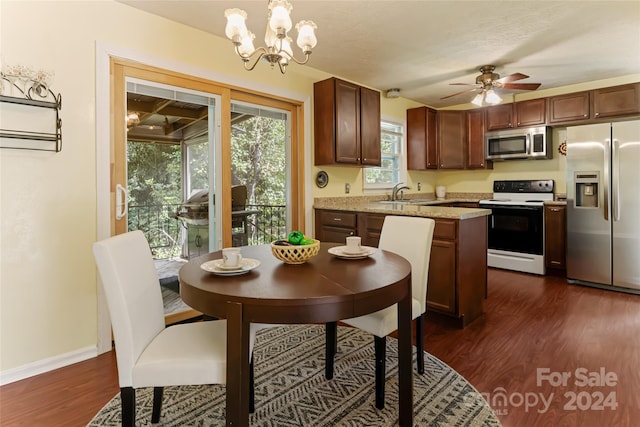 kitchen with ceiling fan with notable chandelier, appliances with stainless steel finishes, hanging light fixtures, and dark hardwood / wood-style floors