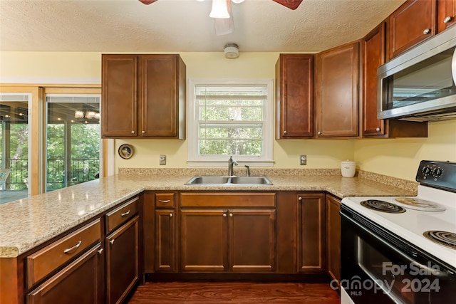 kitchen with light stone counters, white range with electric stovetop, a textured ceiling, dark hardwood / wood-style floors, and sink