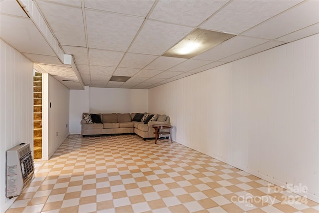 unfurnished living room with wood walls, a paneled ceiling, and heating unit