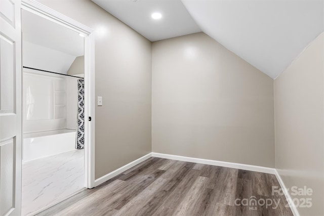 bathroom with wood-type flooring, a shower with curtain, and lofted ceiling