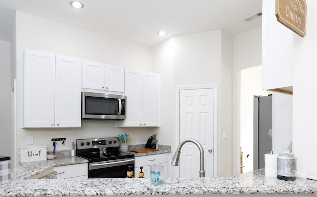 kitchen featuring light stone countertops, appliances with stainless steel finishes, and white cabinetry