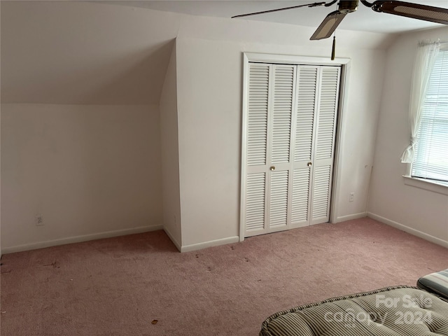 unfurnished bedroom with vaulted ceiling, ceiling fan, light colored carpet, and a closet