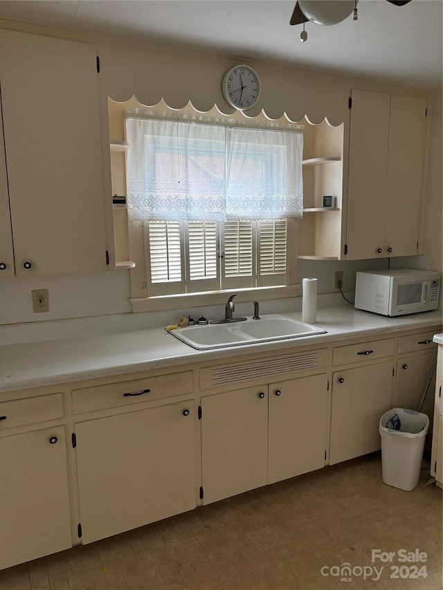 kitchen with sink, ceiling fan, and white cabinets