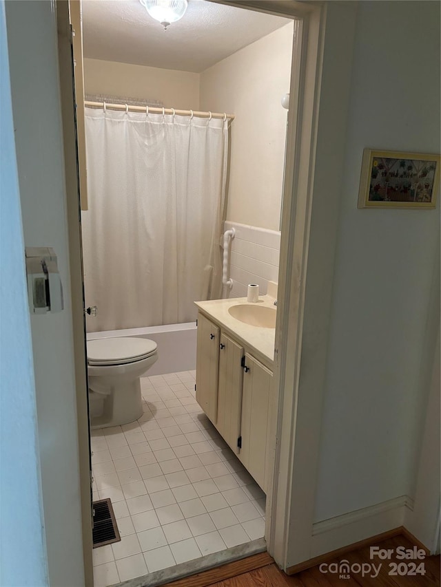 full bathroom with vanity, shower / bath combo with shower curtain, toilet, and tile patterned flooring