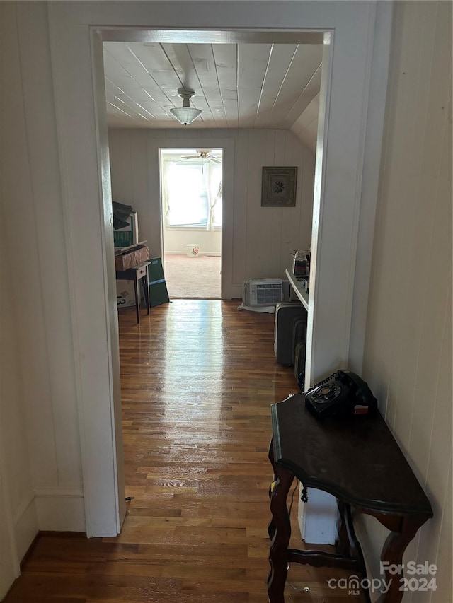 entryway with wood-type flooring, lofted ceiling, and wood walls