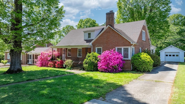 view of front of home featuring an outbuilding, a detached garage, driveway, brick siding, and a front yard
