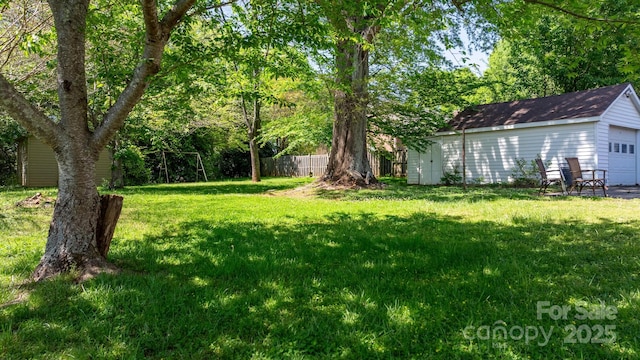 view of yard with an outdoor structure, a detached garage, and fence