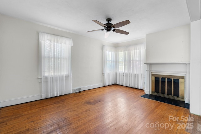 unfurnished living room with a fireplace with flush hearth, baseboards, visible vents, ceiling fan, and wood-type flooring
