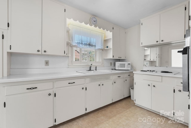 kitchen featuring light countertops, light floors, a sink, and white appliances