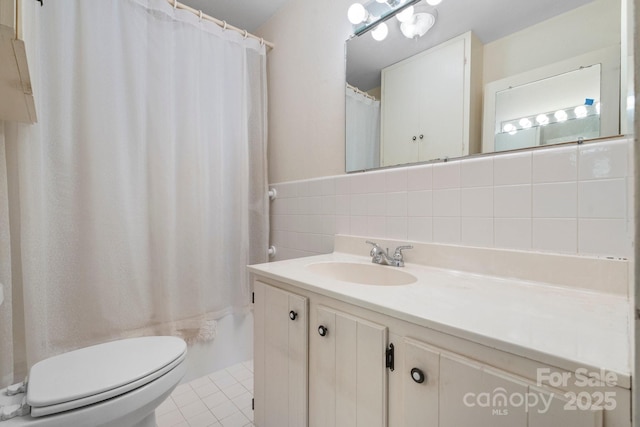 bathroom with tile patterned flooring, toilet, vanity, and tile walls