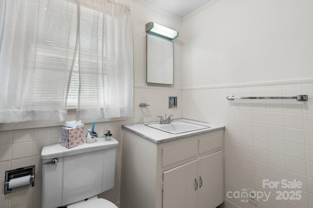 half bath featuring toilet, vanity, ornamental molding, tile walls, and wainscoting