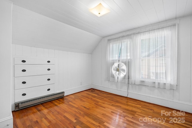 additional living space with a baseboard heating unit, vaulted ceiling, and wood finished floors