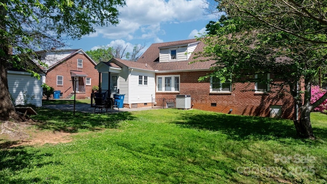 rear view of property featuring crawl space, brick siding, a yard, and cooling unit