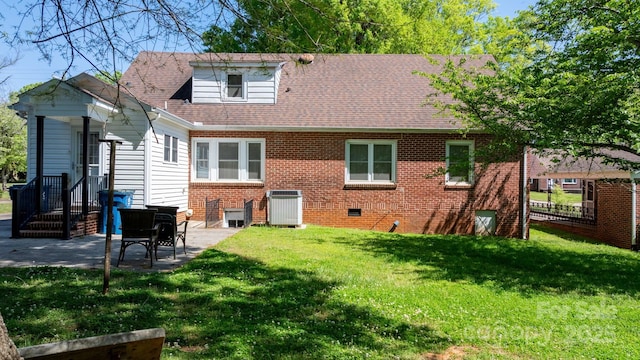 back of house with brick siding, central air condition unit, a yard, a patio, and roof with shingles
